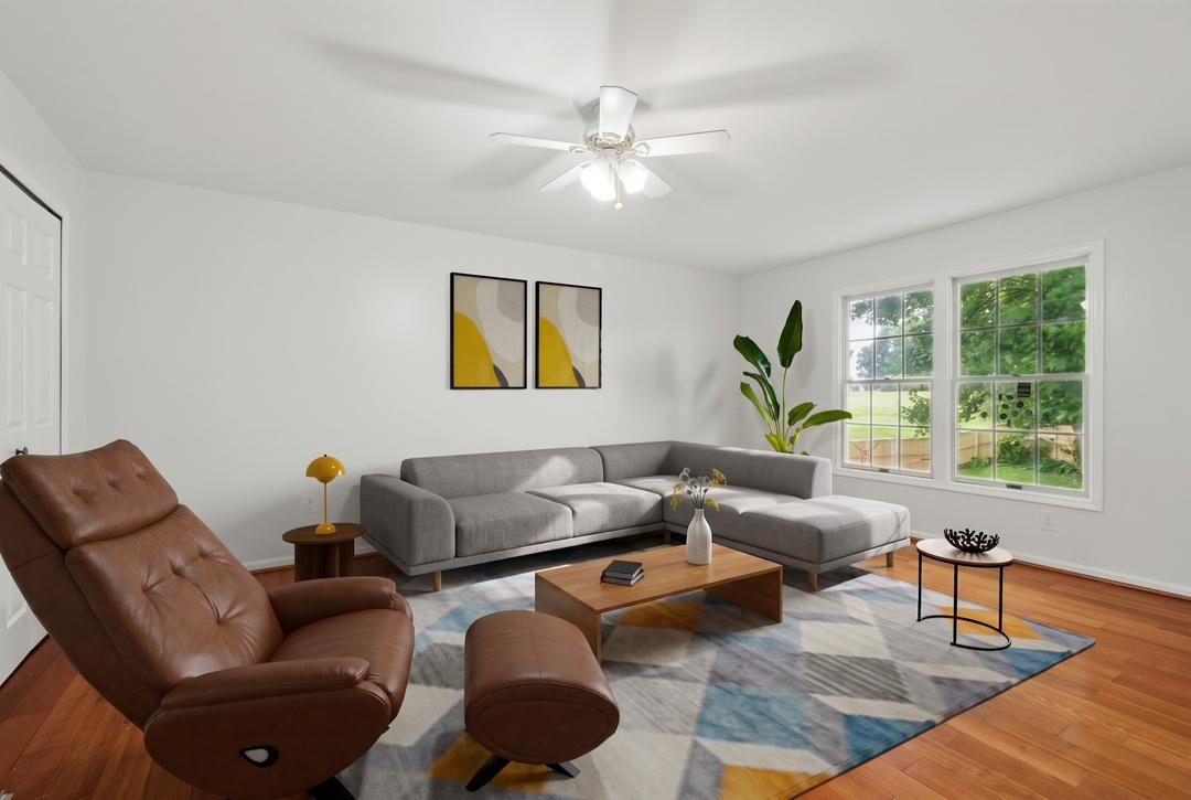 Virtually staged living room seen from the doorway — sofa, armchair and coffee table